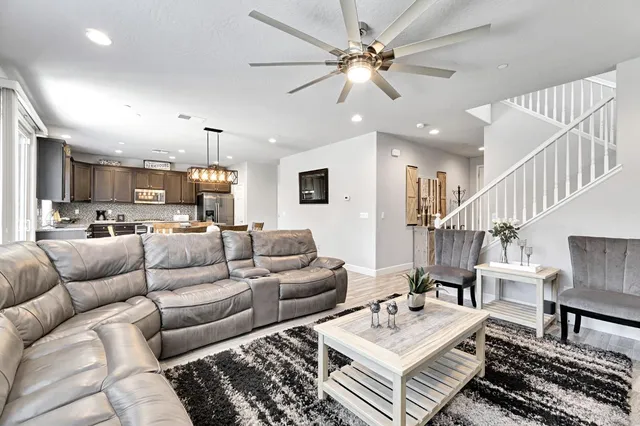 a living room with furniture kitchen view and a chandelier
