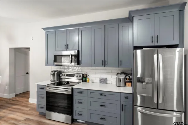 a kitchen with stainless steel appliances a stove a sink a refrigerator a microwave and cabinets