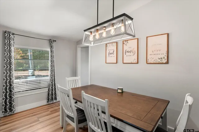 a open kitchen with stainless steel appliances granite countertop a stove refrigerator a dining table and chairs with wooden floor