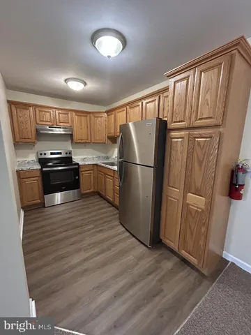 a kitchen with granite countertop a refrigerator stove and wooden floor