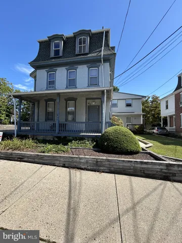 a view of a brick house with a yard plants and large tree
