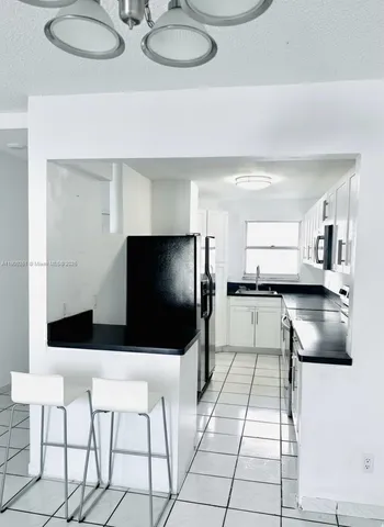 a kitchen with stainless steel appliances kitchen island granite countertop a sink and a white cabinets