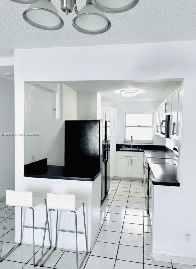 1750 West 46th Street, Unit 535 Hialeah, FL 33012 - Photo 3 of 26 a kitchen with stainless steel appliances kitchen island granite countertop a sink and a white cabinets