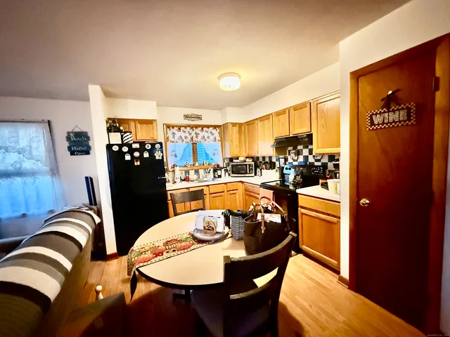 a kitchen with stainless steel appliances granite countertop a dining table chairs and a refrigerator
