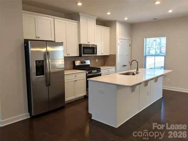 a kitchen with stainless steel appliances a sink a stove a microwave a refrigerator a sink and cabinets