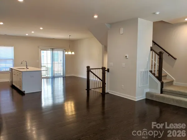 a view of a hallway with wooden floor and a kitchen space