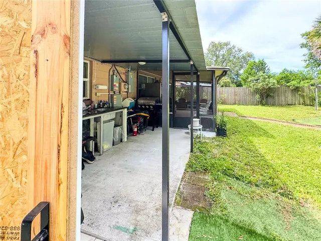 a backyard of a house with lawn chairs and couches with wooden fence