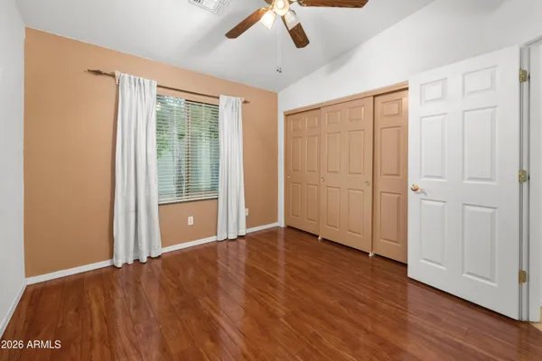 an empty room with wooden floor fan and windows