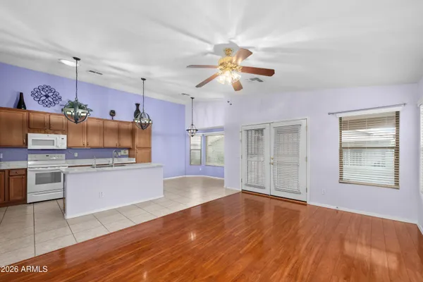 a open kitchen with granite countertop a stove top oven a sink dishwasher and white cabinets with wooden floor