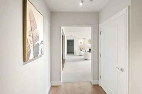 a view of a hallway with wooden floor and a living room