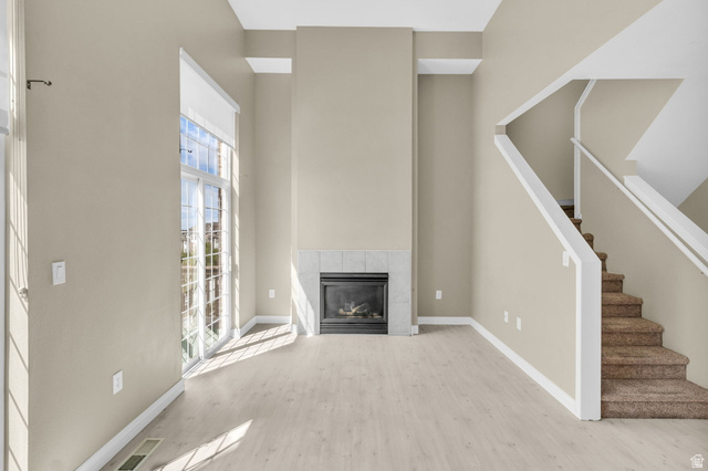 14108 Pepi Band Road Draper, UT 84020 - Photo 6 of 36 Spacious living area featuring a fireplace with a tile surround, large glass sliding doors, and wood-finish flooring