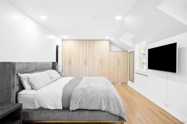 a spacious bedroom with a bed and a flat screen tv