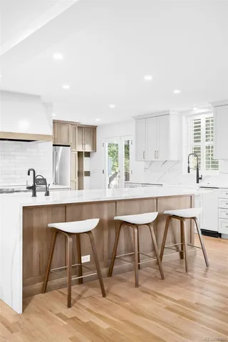 a kitchen with stainless steel appliances kitchen island a table chairs sink and cabinets