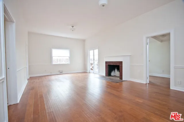 an empty room with wooden floor and fireplace
