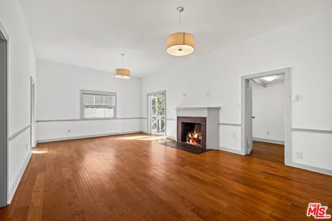 an empty room with wooden floor and fireplace