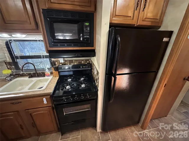 a kitchen with granite countertop a refrigerator stove and sink