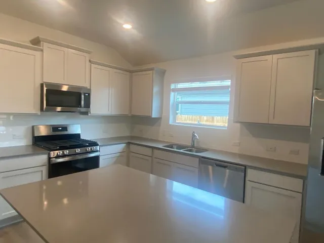 a kitchen with stainless steel appliances a stove a sink a stove a microwave a sink a refrigerator and cabinets