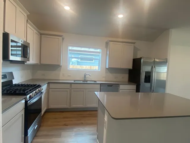 a kitchen with stainless steel appliances granite countertop a sink stove and refrigerator
