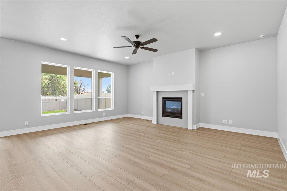 4317 Tropic Way Caldwell, ID 83607 - Photo 4 of 47 Spacious living area featuring wood-finish flooring, a modern fireplace, a ceiling fan, recessed lighting, and multiple windows