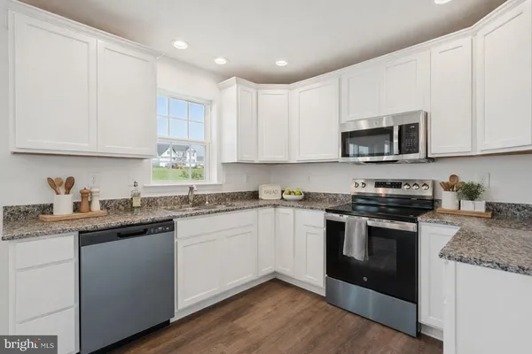 a kitchen with stainless steel appliances granite countertop a stove a sink dishwasher and a microwave oven with wooden cabinets