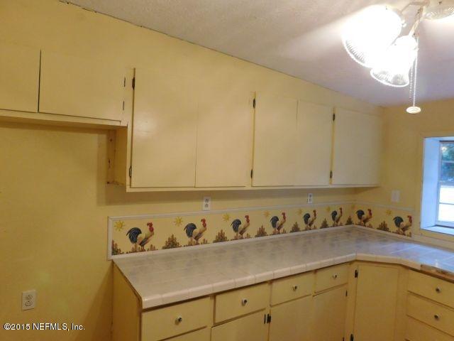 9770 Lily Road Jacksonville, FL 32246 - Photo 29 of 53 a view of a kitchen with white cabinets and a wooden floor