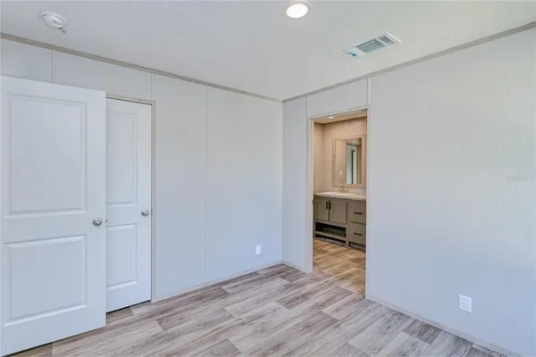 a view of an empty room with wooden floor and closet