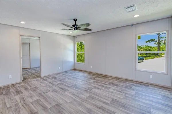 a view of an empty room with window wooden floor and a ceiling fan