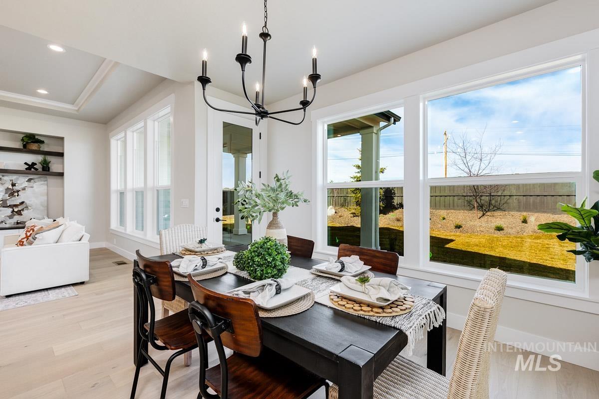 992 East Crescendo Street Meridian, ID 83642 - Photo 14 of 38 Dining room featuring suspended lighting, light wood-type flooring, and a tray ceiling