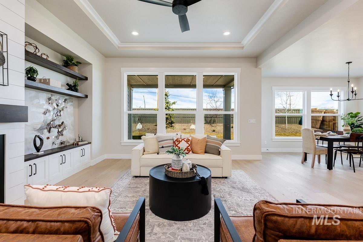 992 East Crescendo Street Meridian, ID 83642 - Photo 16 of 38 Living area featuring a ceiling fan, light wood-style flooring, a fireplace, hanging lights, and a tray ceiling