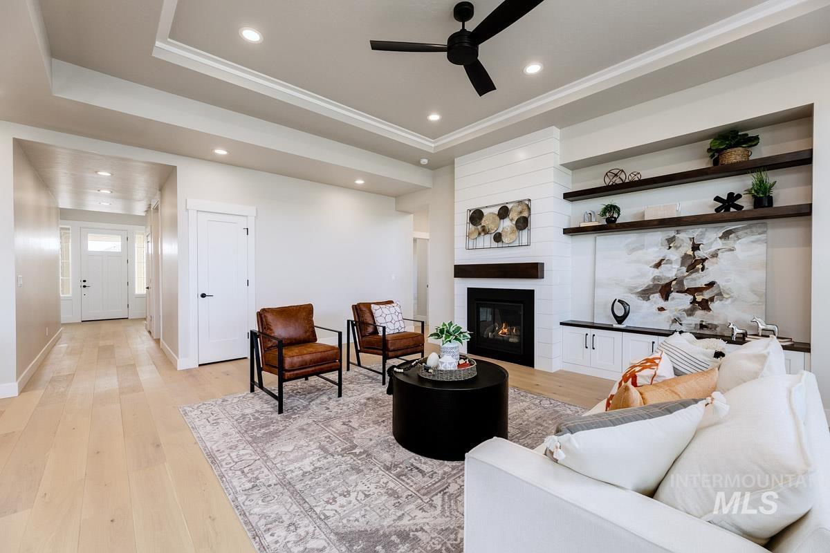 992 East Crescendo Street Meridian, ID 83642 - Photo 17 of 38 Living area with light wood finished floors, a raised ceiling, recessed lighting, a ceiling fan, and a fireplace