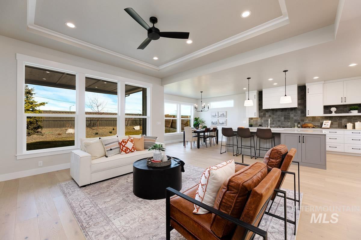 992 East Crescendo Street Meridian, ID 83642 - Photo 18 of 38 Living area featuring a ceiling fan, light wood-type flooring, a raised ceiling, and a chandelier
