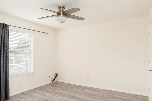 a view of a room with wooden floor and a ceiling fan