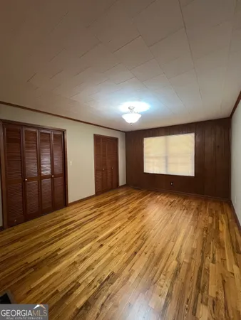 a view of an empty room with window and wooden floor