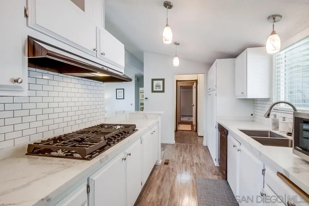 18218 Paradise Mountain Road, Unit 75 Valley Center, CA 92082 - Photo 14 of 68 a kitchen with stainless steel appliances a stove a sink a refrigerator white cabinets and wooden floor