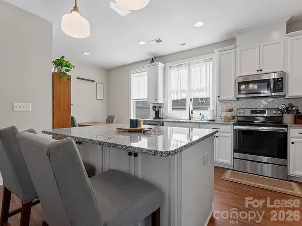 a kitchen with stainless steel appliances granite countertop a sink a stove a microwave a refrigerator cabinets and a window