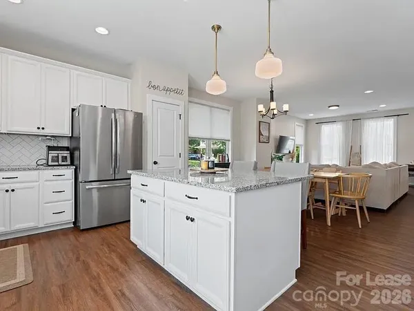 a kitchen with stainless steel appliances granite countertop a refrigerator a sink dishwasher a stove and white cabinets with wooden floor