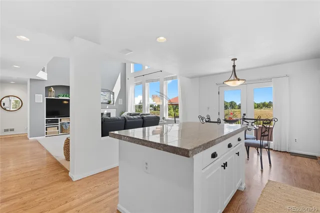 a kitchen with stainless steel appliances granite countertop a sink dishwasher a stove and a dining table with wooden floor