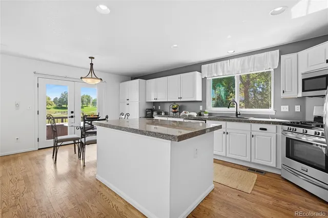 a kitchen with granite countertop a stove a sink a dining table and chairs