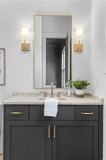 a bathroom with a granite countertop sink a toilet a mirror and shower