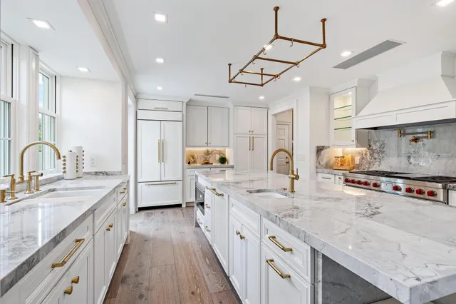 a large white kitchen with granite countertop a large window and white appliances