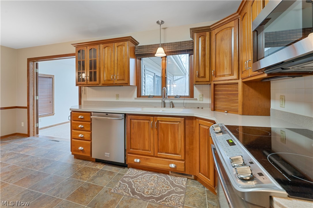 6599 Struthers Road Youngstown, OH 44514 - Photo 13 of 29 Kitchen with stainless steel appliances, wood finish cabinets, glass insert cabinets, tasteful backsplash, and pendant lighting