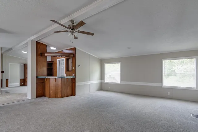 an empty room with chandelier fan and windows