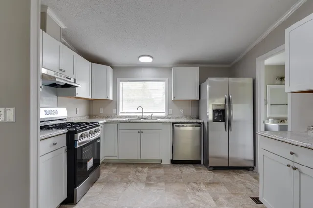 a kitchen with stainless steel appliances granite countertop a stove a refrigerator and a sink