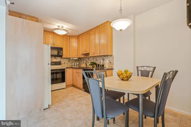 a kitchen with a dining table chairs and refrigerator