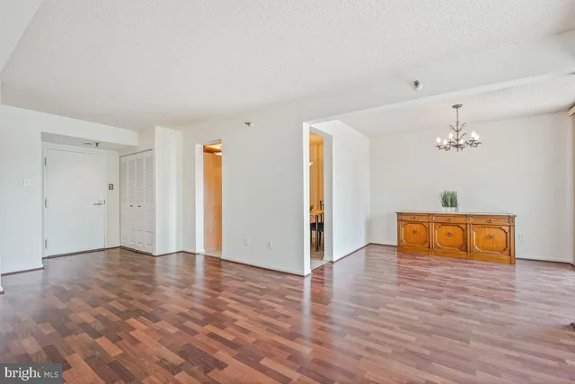 an empty room with wooden floor and chandelier