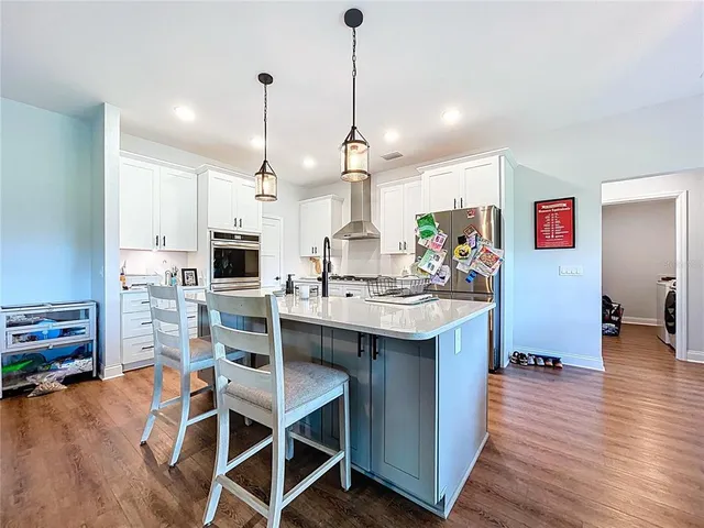 a kitchen with stainless steel appliances kitchen island granite countertop a table chairs in it and wooden floors