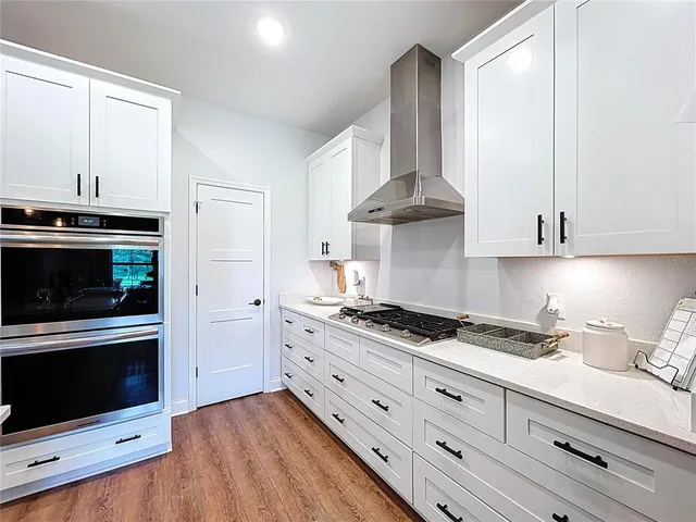 a kitchen with stainless steel appliances a sink a stove and wooden floor