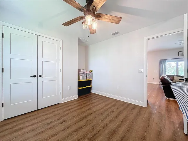 a view of bedroom with wooden floor and ceiling fan