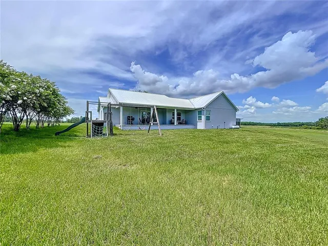 a view of a lake with lawn chairs and large trees