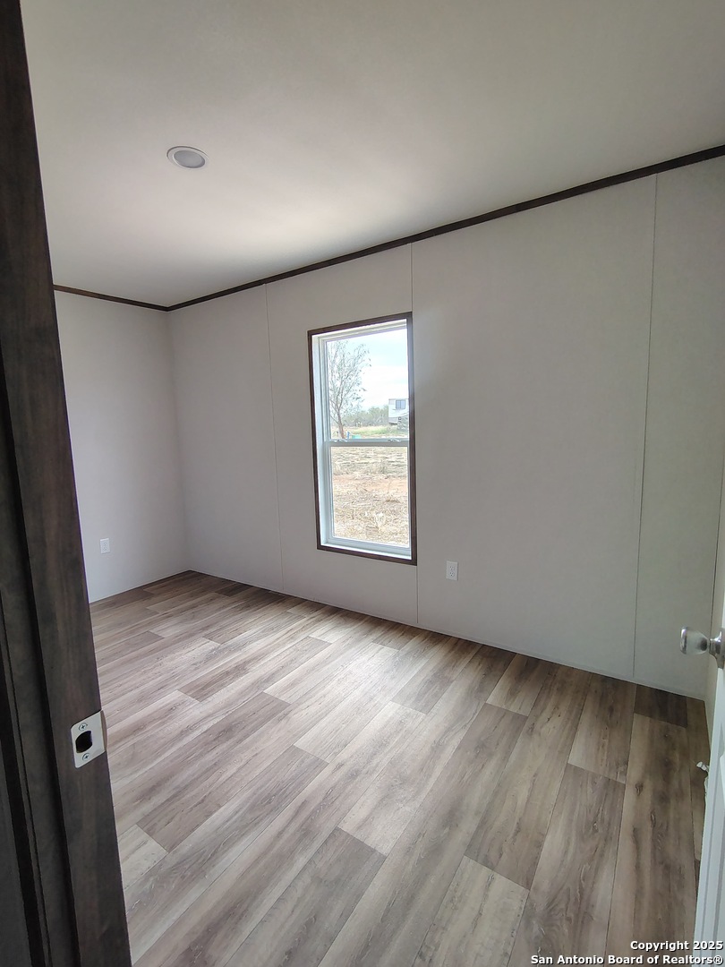 152 County Road 2664 Devine, TX 78016 - Photo 16 of 17 an empty room with wooden floor and windows